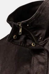 Cazadora de efecto ante en color marrón oscuro, con cuello subido, manga larga y cierre frontal con cremallera y botones a presión. Presenta bolsillos de vivo en el delantero y dobladillo elástico.
