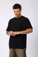 Remera de corte oversize color negro, con cuello redondo y detalle de costura en forma de X en el frente.