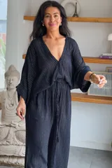 Conjunto de camisa y pantalón de viscosa negro con finas líneas metalizadas doradas. La camisa es de manga larga con escote en V y botones frontales, mientras que el pantalón es de corte ancho y tiro alto con cintura elástica fruncida.