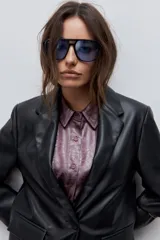 Blazer de cuero sintético negro con solapas clásicas, cierre de un botón y bolsillos frontales con solapa.