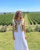 Chaleco color crudo con bordados botánicos en color tabaco, sin mangas y con diseño abierto.