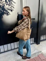 Camisa de corte holgado con estampado de cuadros escoceses en tonos beige y marrón. Presenta cuello clásico, cierre frontal con botones y mangas largas.