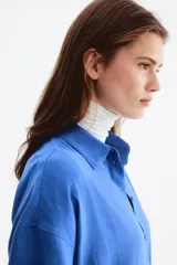 Camisa de lino y viscosa color azul, de corte oversized y diseño liviano, con cuello clásico, cierre frontal de botones, hombros caídos y mangas largas con puños abotonados.