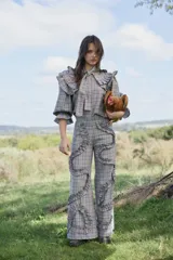 Pantalón de tiro alto con diseño de cuadros en tonos grises y naranjas, corte recto y amplio, decorado con volados aplicados en forma sinuosa a lo largo de las piernas.