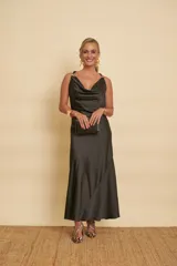 Vestido largo negro de satén, con escote drapeado, tirantes finos con detalle de argollas doradas y falda de corte evasé.