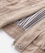 Campera de sarga color beige con corte oversized, cuello de cuero sintético negro con textura trenzada, cierre frontal oculto y bolsillos laterales.