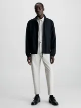 Campera negra de nailon arrugado reciclado, con cuello alto, puños y bajo elásticos, cierre con cremallera, bolsillos con cremallera en la cintura, abertura de ventilación en la espalda, forro de poliéster reciclado e insignia con el logo de goma de Calvin Klein en la manga.