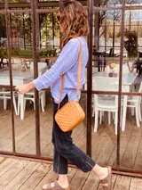 Bandolera color naranja de cuero con diseño capitoneado en forma de V.