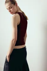 Top de punto color crema, sin mangas, con cuello redondo y corte ajustado.