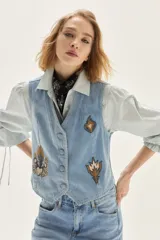 Chaleco de denim celeste con bordados decorativos en el frente, cierre de botones y corte entallado.