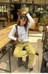 Pantalón de tiro medio color verde oliva, confeccionado en tejido con efecto gamuza. Presenta cierre frontal con cremallera, presillas para cinturón y corte recto.