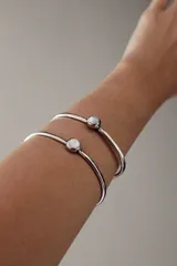 Pulsera rígida plateada con aplique circular de nácar.