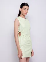 Vestido corto sin mangas, ajustado al cuerpo, color verde claro con estampado de cuadros vichy blancos. Presenta un corte en la cintura que deja ver parte del costado.