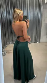 Conjunto de dos piezas color verde oscuro, compuesto por un top tipo bralette con cuello halter y un dije ovalado blanco en el centro, y una falda larga y fluida.