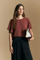 Top de manga corta con escote redondo y silueta relajada, confeccionado en tela fluida con detalle de pliegues en las mangas.