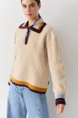 Buzo de lana tipo polo con cuello y cartera de botones en colores contrastantes. Presenta mangas con tejido de ochos y terminaciones en puños y ruedo con franjas de colores.