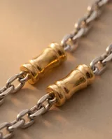 Cadena de acero combinada con eslabones plateados y apliques cilíndricos dorados intercalados.