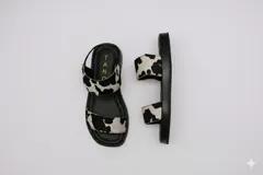 Sandalias bajas con suela negra y tiras de cuero con estampado de vaca.