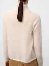 Sweater de punto cardado con textura suave y esponjosa, cuello chimenea y manga larga. Presenta un diseño minimalista y elegante con etiqueta logotipada en la espalda.