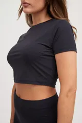 Remera corta negra ajustada al cuerpo, confeccionada en tejido suave con protección UV50+.