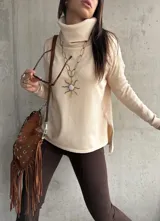 Polera de tejido de punto color beige, con cuello alto, mangas largas y aberturas laterales en el ruedo.