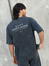 Remera gris con efecto gastado, corte oversize, mangas cortas y estampado en la espalda con el texto "SUPPLY GOODS DESIGNED IN PUNTA DEL ESTE".