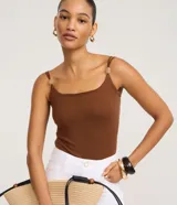 Body femenino ajustado, sin mangas, color verde oliva, con escote cuadrado y breteles finos dobles adornados con piezas decorativas. El tejido es texturizado.