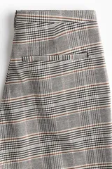 Pantalón sastrero de tiro alto con piernas amplias y pliegues frontales. Presenta un estampado de cuadros Príncipe de Gales en tonos grises, beige y negro.