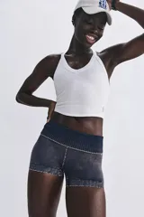 Top deportivo blanco, ajustado al cuerpo, con escote en V pronunciado en el frente y espalda tipo racerback. Presenta tejido acanalado.