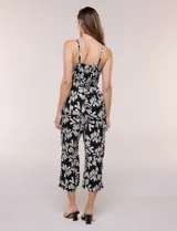 Enterito crop de rayón con estampado geométrico en blanco y negro, busto elastizado con frunces, breteles finos regulables y cordón ajustable en la cintura con terminaciones de borlas. Pantalón de corte amplio y relajado.