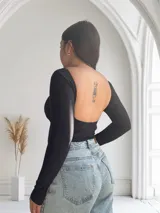 Body negro de mangas largas con escote en V y detalle de tul transparente en el centro.