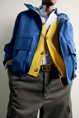 Cazadora técnica relaxed fit de color azul, con cuello subido, capucha ajustable, bolsillos frontales de plastrón con solapa, cierre de cremallera oculta y puños elásticos.