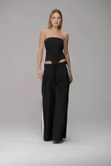 Pantalón wide leg de color negro con franjas laterales blancas, corte de tiro medio, cintura con cordón ajustable y pinzas frontales que aportan volumen y caída fluida.