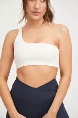 Top deportivo blanco de un solo hombro, con elástico en el contorno superior y sostén interno en el lado derecho.