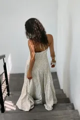 Vestido midi de corte fluido con escote halter y lazada ajustable al cuello. Presenta un diseño con estampado de lunares y falda con volumen.