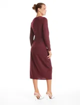Vestido midi de seda fría color bordó, con cuello a la base, mangas largas y detalle de lazo ajustable en la cintura que crea un efecto drapeado lateral.