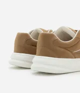 Championes de estilo skater para hombre, confeccionados en poliuretano color marrón oscuro. Poseen punta redonda, caña baja y suela de plataforma blanca. Destacan por sus cordones anchos tipo fat lace y detalles laterales en contraste.