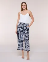 Pantalón crop ancho en color negro con estampado floral en contraste, bolsillos laterales y detalle de encaje en el ruedo.