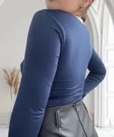 Body azul con escote cuadrado y mangas largas. Presenta dos hebillas doradas en el frente.