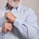 Camisa de vestir celeste a rayas verticales blancas, de corte clásico, con cuello abotonado y manga larga.