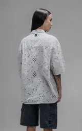 Camisa de manga corta y corte holgado con diseño de bordado broderie en toda la prenda, cuello camisero y cierre frontal de botones.