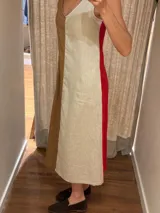 Vestido midi de lino con diseño bicolor dividido en tonos beige y marrón, escote en V, sin mangas y corte holgado con bolsillos laterales.