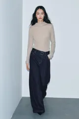 Jeans de tiro alto con pierna ancha, confeccionados en denim azul oscuro. Presentan cinco bolsillos, trabillas en la cintura y un cinturón ajustable del mismo tejido con hebilla metálica. Incluyen pespuntes marcados a tono y cierre frontal con cremallera y botón.