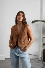 Chaleco de gamuza color marrón con bordados florales en tono oscuro y cierre frontal mediante lazos.