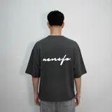 Remera gris de algodón, corte oversize, con mangas cortas y estampado en la espalda con la palabra 'nenefa' en cursiva blanca.