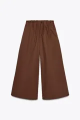 Pantalón marrón oscuro, tipo culotte, de tiro medio con cintura elástica fruncida y pierna ancha. Posee bolsillos laterales ocultos en la costura.