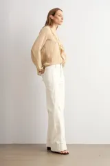 Pantalón de jean wide leg en color blanco, de tiro alto y corte ancho con dobladillo ancho en los bajos.