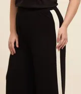 Pantalón pantacourt negro con raya lateral blanca, confeccionado en viscosa y elastano.