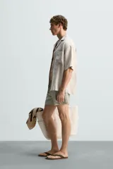 Bañador de hombre color verde claro con finas rayas blancas verticales (efecto seersucker). Tiene cintura elástica ajustable con cordón verde, bolsillos laterales y un bolsillo trasero de vivo.
