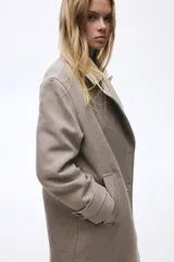 Abrigo cruzado de lana hasta la rodilla, con solapas de muesca, cierre de doble botonadura frontal y bolsillos insertados. Presenta trabillas con botón en los puños y abertura posterior, completamente forrado.